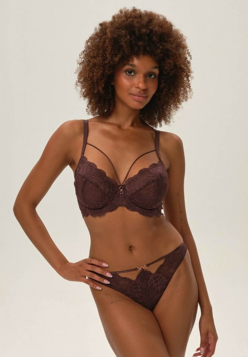 Brązowy koronkowy bralet z regulowanymi ramiączkami i ozdobnym złotym akcentem, w zestawie z dopasowanym koronkowym thongiem z wąskimi ramiączkami.