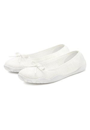 Chaussures blanches plates avec un dessus en tricot texturé, détail en nœud au bout et une semelle en caoutchouc blanc flexible pour le confort et la facilité de mouvement.