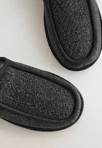 Pantofole nere e grigie con motivo, dal tocco morbido, punta arrotondata e bordi neri; presentano un design accogliente e strutturato.