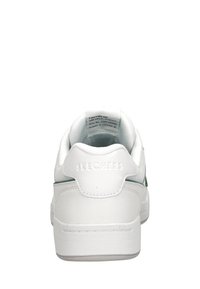 Sneaker bianco in materiale sintetico liscio, con forma arrotondata, collo imbottito, logo impresso e accento verde lungo il lato.