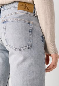 Világoskék denim farmernadrág, laza szabással, barna bőr Calvin Klein Jeans címkével és klasszikus öt zsebes dizájnnal. Puha tapintás.