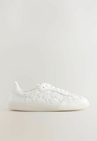 Hvide sneakers med snørebåndsoverlag, glatte læderdetaljer, rund tå og seks øjer til snørebånd. Fleksibel gummisål med struktureret greb.