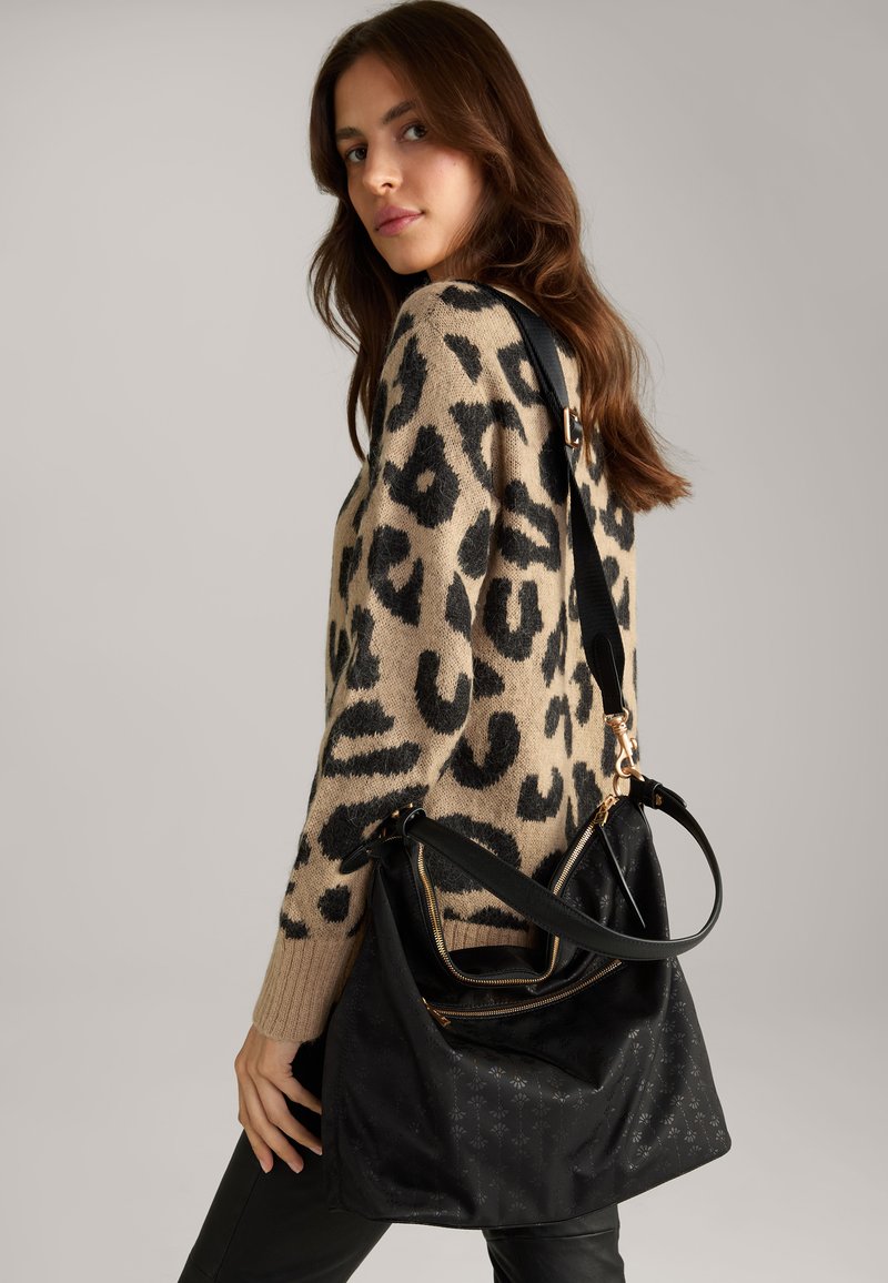 Borsa nera con una texture morbida, hardware dorato e una tracolla. La borsa presenta una chiusura a zip e dettagli decorativi sul tessuto.