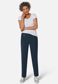 Marineblauwe broek met minimalistisch ontwerp en zijzakken, gecombineerd met een wit T-shirt met korte mouwen en grijze sneakers.