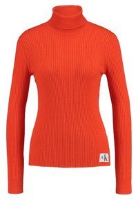 Pull à col roulé côtelé orange avec manches longues, présentant une coupe ajustée et une étiquette avec le logo CK en bas à gauche.