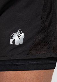 Zwarte sportshorts van een gladde stof met een zilveren afbeelding van een gorilla. Zijpanelen zijn gemaakt van mesh voor ademend vermogen.