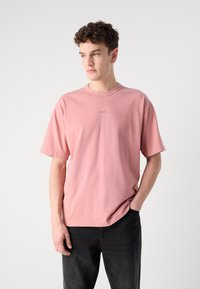 Rosa bomulds T-shirt med korte ærmer og rund hals; har et lille præget logo på brystet og en afslappet pasform.
