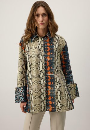 Majica z dolgimi rokavi z mešanico vzorca kače in živih geometrijskih vzorcev. Ima ovratnik in vzorčaste manšete.