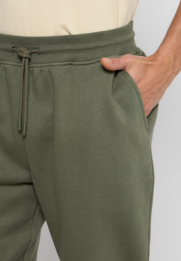 Pantaloni da tuta in cotone misto verde oliva con vita a coste, chiusura con cordino e tasche laterali. Morbido al tatto e vestibilità rilassata.