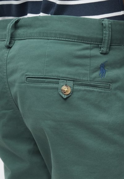 Πράσινο βαμβακερό παντελόνι με κουμπωτή πίσω τσέπη και κεντημένο λογότυπο. Το ύφασμα είναι λείο με απαλή υφή και καλοραμμένη εφαρμογή.
