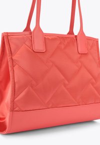 Koraal kleurige gewatteerde tote bag met een gladde bodem, dubbele platte handvatten en een rechthoekige vorm. Heeft een gestikt ruitpatroon en een zachte textuur.