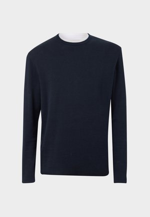 Marineblå langermet genser med rund hals i lett strikket materiale. Har en kontrasterende hvit indre krage og en rett nederkant.