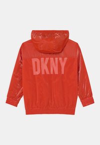 Czerwona wodoodporna kurtka z panelem z siateczki, elastycznymi mankietami i kapturem ze sznurkiem. Na plecach duży nadruk z logo "DKNY".
