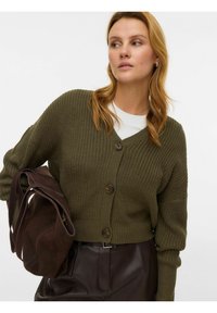 Cardigan in maglia verde oliva con scollo a V, tre grandi bottoni e maniche lunghe; abbinato a una borsa a tracolla marrone scuro.