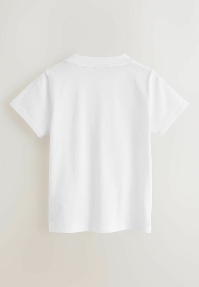 Polo bianca semplice a maniche corte vista da dietro su uno sfondo chiaro e neutro.