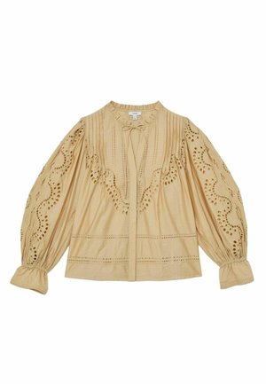 Blouse beige à manches longues avec détails en dentelle à œillets, col volanté, plis pincés et cordon à nouer au niveau de l’encolure.