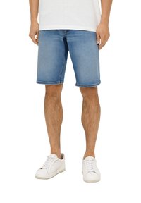 Jasnoniebieskie szorty dżinsowe o prostym kroju, z postrzępionym dołem i przeszyciami, w połączeniu z białymi trampkami.