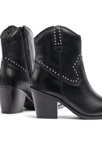 Botines de cuero negro con remaches plateados decorativos, punta afilada y tacón grueso. Cremallera lateral para un uso fácil y un acabado suave.