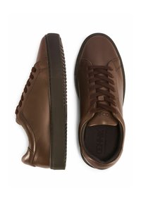 Brązowe skórzane sneakersy na sznurówki z czarną gumową podeszwą, jeden but pokazany od góry, drugi z boku na białym tle.