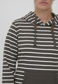 Grå hettegenser med hvite horisontale striper. Har en frontlomme, snor med brune detaljer, og en myk tekstur.