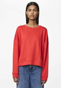 Sudadera roja con un corte relajado, escote ancho y mangas largas. Fabricada con un tejido suave y texturizado, presenta un diseño corto.