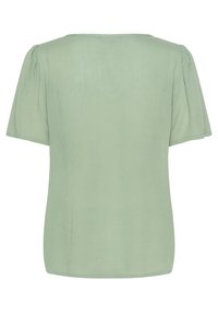 Haut à manches courtes en vert clair, texture lisse, col rond, manches légèrement bouffantes et ourlet droit sans motifs ni accessoires visibles.