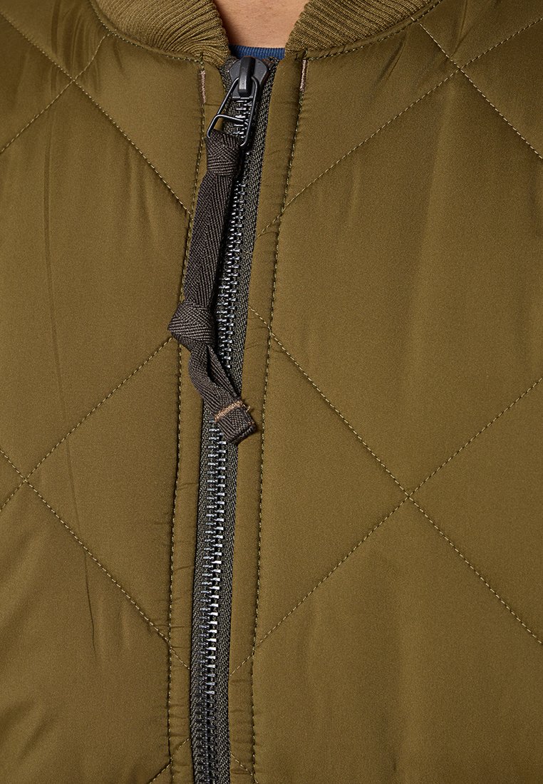 Gep padded olivgrüne Jacke mit einem zentralen Reißverschluss mit Zipper, geripptem Kragen und robuster Stoffstruktur.