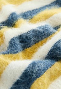 Una tela de rayas multicolores presenta tonos de azul, amarillo y blanco. La textura es peluda, con fibras suaves y mezcladas que crean una apariencia cálida.