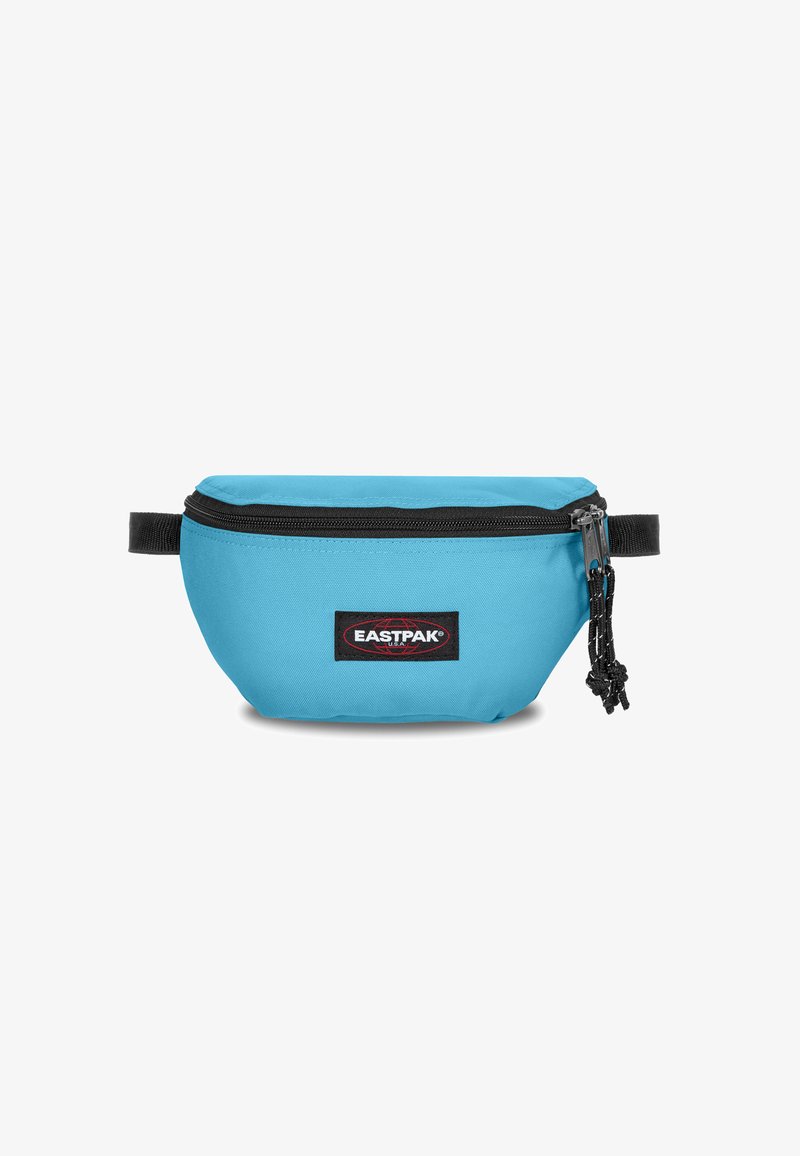 Blue canvas fanny pack with a black zipper and logo patch. Features a rounded shape and adjustable strap for secure wearing.
