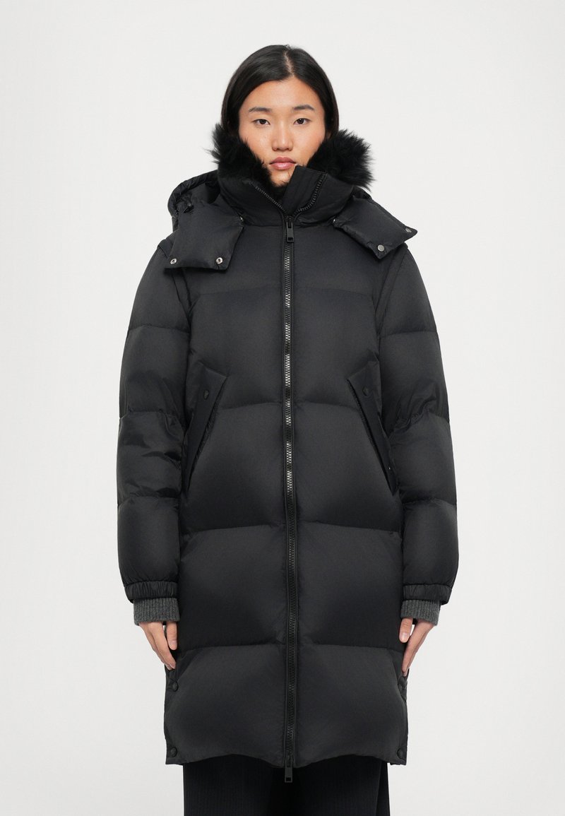 Schwarze Daunenjacke mit Reißverschluss vorne, abnehmbarem Kapuzen und Kunstfellbesatz. Mit einem gesteppten Design und seitlichen Taschen. Glatte Textur.