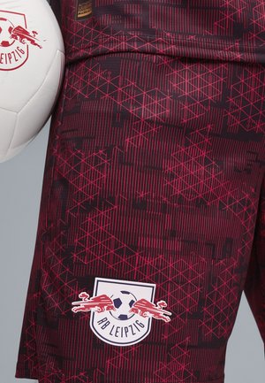 Røde og sorte shorts med geometriske mønstre, prydet med et RB Leipzig-logo og en hvid fodbold, lavet af letvægtsmateriale.
