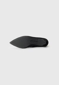 Chaussure noire à talons aiguilles avec un bout pointu et une semelle en caoutchouc. Le matériau semble doux et texturé, avec un détail de marque sur la semelle.