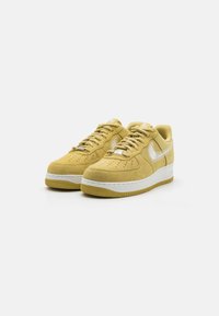 Yellow suede sneakers with white accents, rounded toe, perforations on the toe box, and textured rubber outsole. Laces are matching yellow.