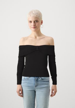 Juodas off-the-shoulder marškinėliai su ilgomis rankovėmis, turintys susuktą centrą. Pagaminta iš tamprus audinys, prigludusi siluetas. Suderinta su šviesiai mėlynais džinsais.