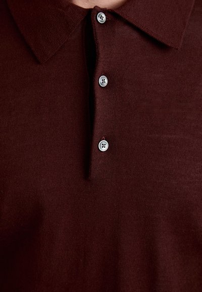 Bordeauxrotes Polohemd mit Kragen, ausgestattet mit einer durchgehenden Knopfleiste und vier silberfarbenen Knöpfen. Strickstruktur mit glatter Oberfläche.