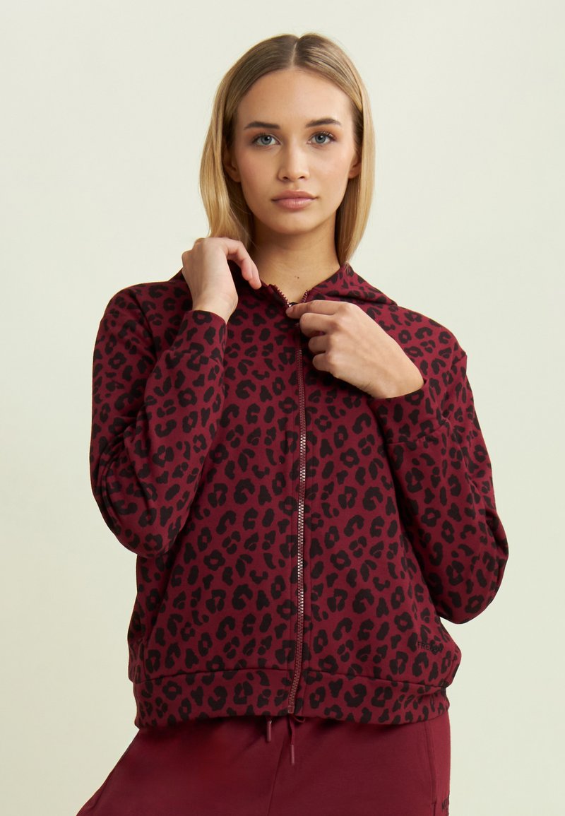 Sudadera con cremallera de color marrón burdeos con estampado de leopardo negro. Presenta capucha, mangas largas y puños de canalé. Tejido suave con un ajuste holgado.