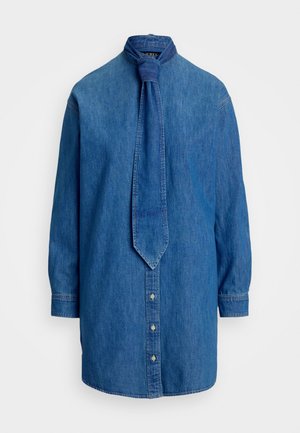 Camisa de ganga azul, com colarinho alto e um laço atado. Fecho de botão na frente e mangas longas com punhos abotoados.