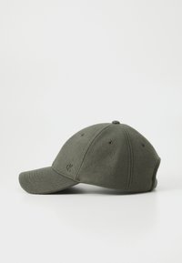 Casquette en laine verte avec une couronne arrondie, un bord incurvé et un logo discret sur le côté. Comprend des œillets respirants pour la ventilation.