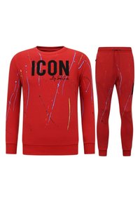 Rode trainingsoutfit bestaande uit een sweatshirt met ronde hals met "ICON" gedrukt in het zwart en spetters verfaccenten, gecombineerd met bijpassende tapered broek.