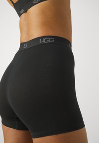 Crne UGG bokserice od mekog, rastezljivog materijala s glatkom teksturom i pojasom s logotipom.