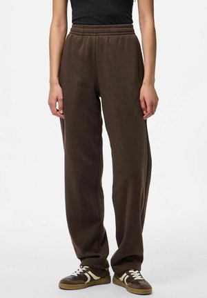 Brown sweatpants with an elastic waistband, featuring a relaxed fit and smooth texture, paired with dark sneakers with white accents.