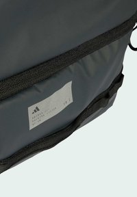 Tamno sivi Adidas ruksak s crnim detaljima, prednji džep sa zatvaračem i oznakom "Adidas Packing System DF50 501."