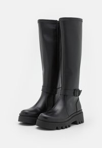 Μαύρες μπότες μέχρι το γόνατο από λεία δερμάτινη επιφάνεια, με πλευρικό φερμουάρ, λουρί με αγκράφα και παχιά, ραβδωτή καουτσούκ σόλα.