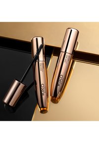 Deux tubes de mascara KIKO Milano avec des caps en rose doré brillant, l'un avec une brosse noire. Posés sur une surface réfléchissante noire et dorée.