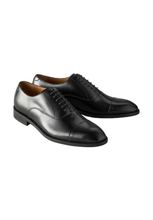 Črne usnjene oblečne čevlje z gladko površino, zaobljenim nosom in okrasnim vezanjem. Imajo nizko peto in kontrastno šivanje vzdolž podplata.