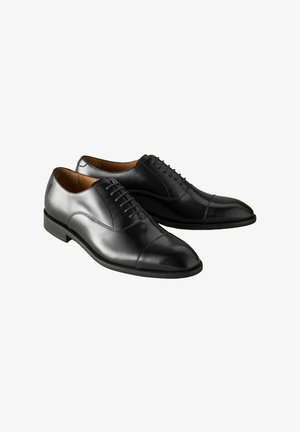 Juodos odinės elegantiškos bateliai su lygia apdaila, apvaliu pirštu ir dekoratyviomis raištelėmis. Turintys žemą kulną ir kontrastingas siūles palei padą.