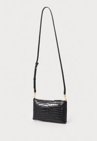 Bolsa de mão em pele com textura de crocodilo preta, com fecho tipo zip, forma retangular slim, alça ajustável e detalhes em metal dourado.