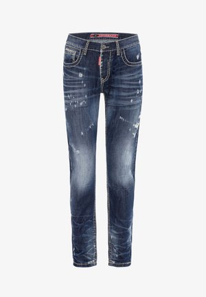 Dunkelblaue Denim-Jeans mit schmalem Schnitt, die mit abgenutzten Details, leichter Verblassung und kontrastierenden weißen Nähten entlang der Nähte ausgestattet sind.