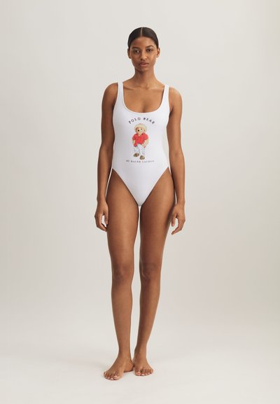 Vit baddräkt i ett stycke med tryckt tecknad björn och texten "POLO BEAR BY RALPH LAUREN." Rund halsringning och figursydd design.