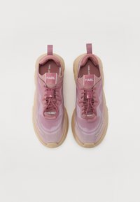 Rosa strikkede sneakers med et strukturert design, kontrasterende tan gummisåler, lisser og merking på tungen og siden.